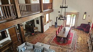 Un loft spacieux avec de hauts plafonds, un coin repas agrémenté d’un tapis rouge et un coin salon confortable avec un canapé et un pouf.