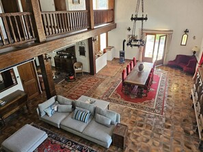 Ein geräumiger Loft mit hohen Decken, einem Essbereich mit rotem Teppich und einer gemütlichen Sitzecke mit Sofa und Hocker.