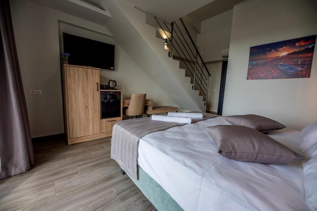 Une chambre à coucher avec un lit, un bureau, une chaise, une télévision et un escalier.