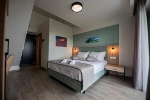 A modern hotel room with a bed, bedside table, and artwork on the wall. - Calda Resort (Polygyros)