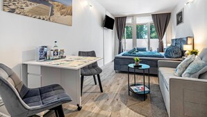 Une chambre moderne équipée d’un bureau, d’une chaise, d’un canapé et d’un téléviseur fixé au mur.