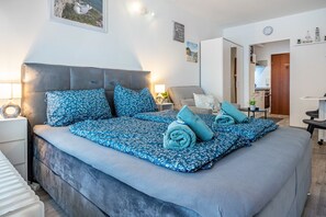 Un dormitorio ordenado con una cama grande, mesitas de noche, una lámpara y vista a la habitación contigua.
