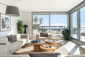 Ein modernes Wohnzimmer mit einer Couch, einem Couchtisch und Blick ins Freie.