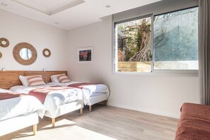 Ein Schlafzimmer mit zwei Betten, einem großen Fenster und Blick auf Bäume.