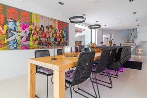 Un espace repas moderne avec une table en bois, des chaises noires et une fresque colorée sur le mur.