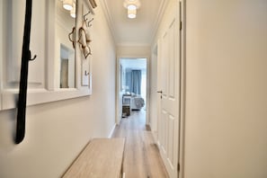 A hallway with a wooden floor, white walls, and a bed visible in the distance. - Beach shell 1 - Live directly on the beach - dreamlike vacation accommodation with (Scharbeutz)