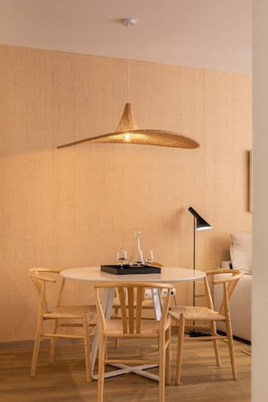 Ein Essbereich mit einem runden Tisch, vier Stühlen, einer Pendelleuchte und einer Stehlampe.