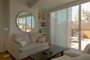 Ein Wohnzimmer mit Sofa, Couchtisch, Spiegel und Blick ins Freie.