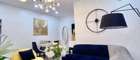 A modern living room with a sofa, armchairs, a coffee table, and a chandelier.