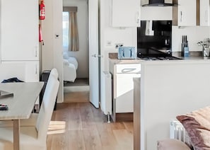 A compact kitchen with a stove, a toaster, and a refrigerator. - 2 bedroom accommodation in Looe (Looe)