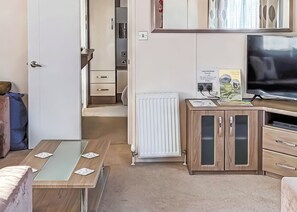 A compact room with a bed, a small table with cards, a radiator, a cabinet with a TV, and a door leading to another room. - 2 bedroom accommodation in Looe (Looe)