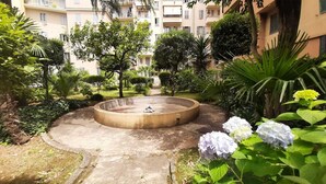 A courtyard with a circular water feature, surrounded by greenery and a building in the background. - D&R Apartment - Metro Re di Roma (Rome)
