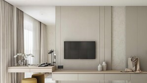 Una habitación de hotel moderna con una gran televisión de pantalla plana en la pared, un escritorio con lámpara y una silla.