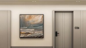 Un pasillo con un cuadro abstracto enmarcado, una puerta con la etiqueta 'C06' y una pared de color claro.
