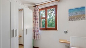 Une chambre avec une fenêtre, un radiateur, un lit et une armoire.