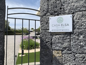 Eine Steinsäule mit einem Metallgitter und einem Schild mit der Aufschrift 'CASA ELISA' und Kontaktinformationen.