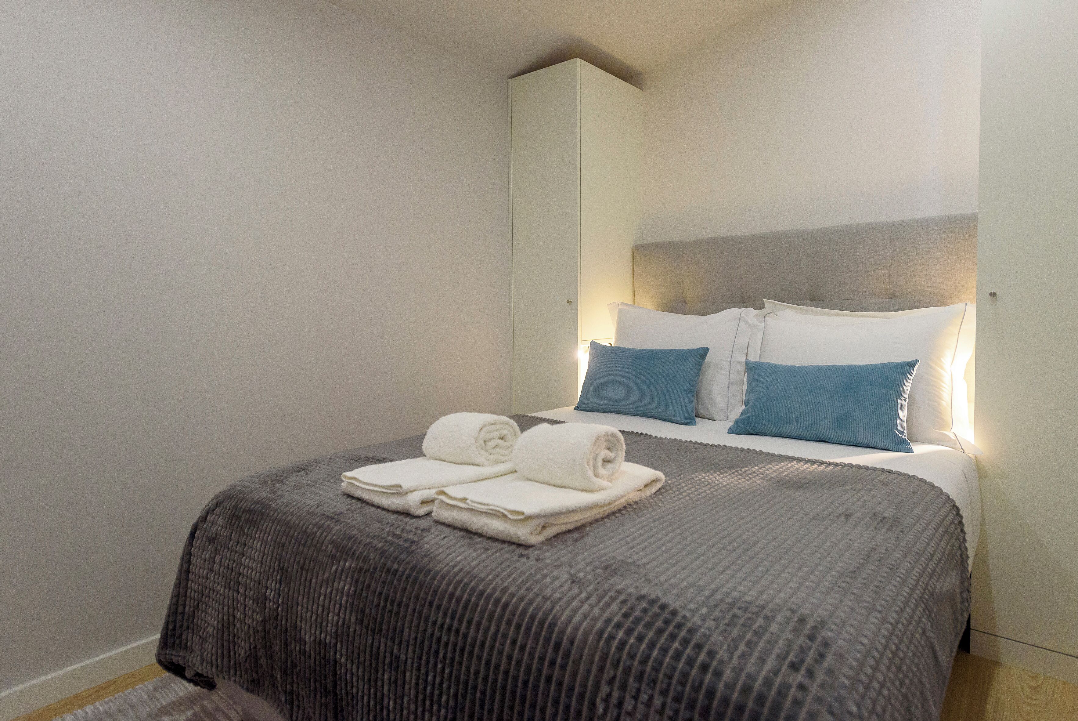 A hotel room with a bed, pillows, and a folded towel on the bed.