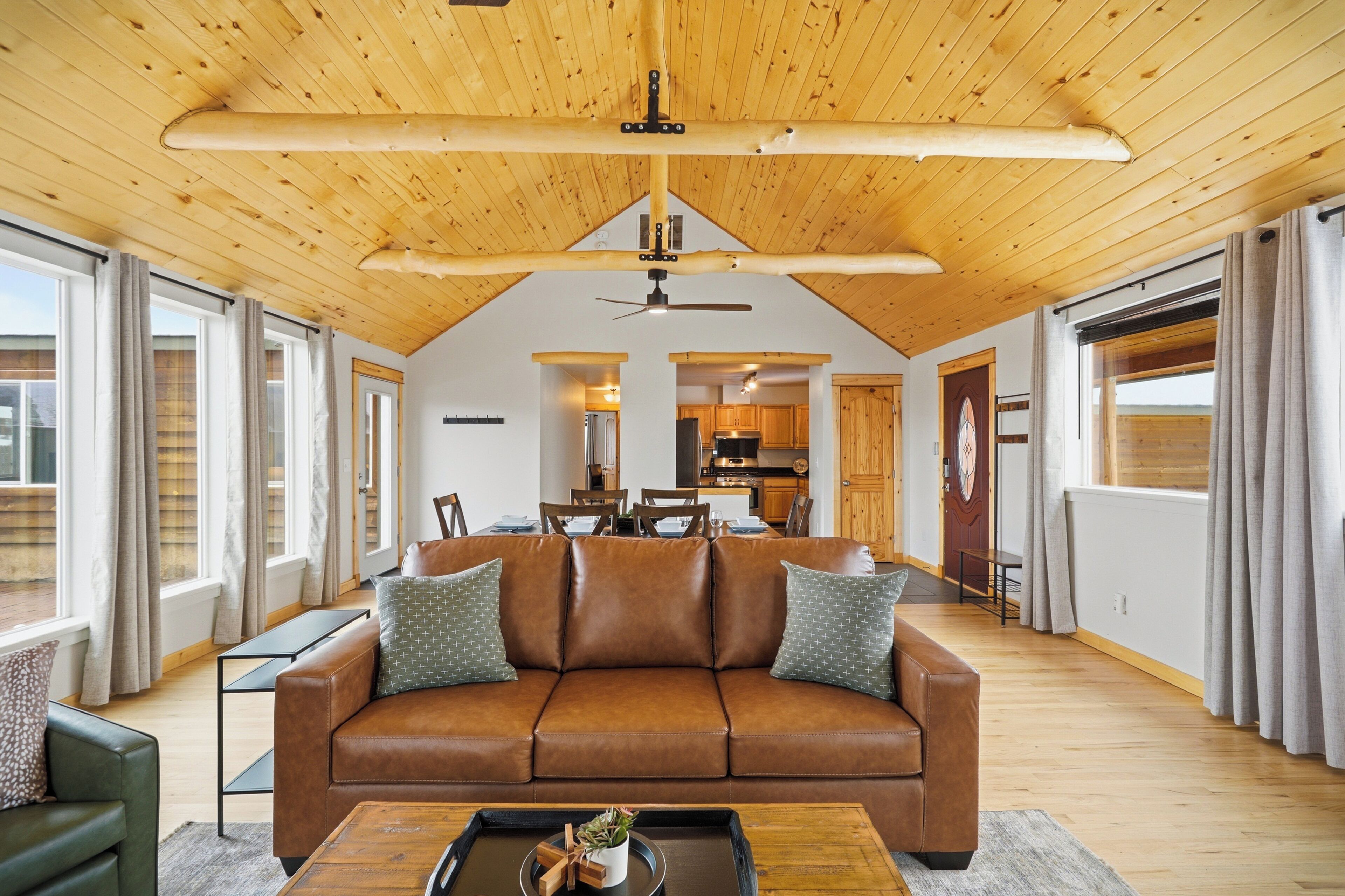A spacious living area with a wooden ceiling, a brown leather sofa, and a dining table.
