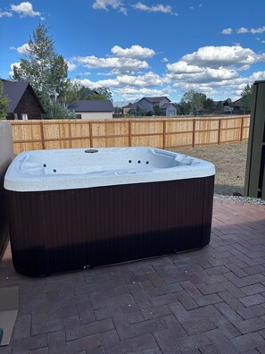 Un jacuzzi en un entorno exterior con un cercado de madera y casas al fondo.