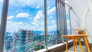 A balcony with a view of a cityscape, a chair, and a table. - Titiwangsa Core at TR Residence by HCK (Kuala Lumpur)
