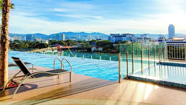 A rooftop pool with lounge chairs, palm trees, and a cityscape view. - Titiwangsa Core at TR Residence by HCK (Kuala Lumpur)