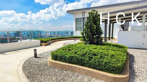 A rooftop terrace with a view of the city skyline, a modern building, and a landscaped garden area. - Titiwangsa Core at TR Residence by HCK (Kuala Lumpur)