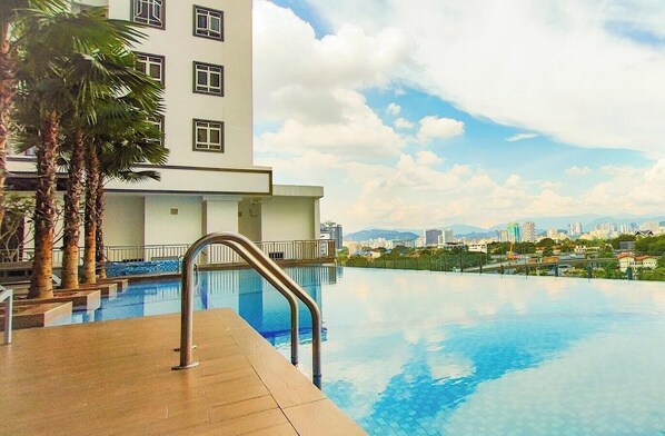 Una piscina con vista a la ciudad, un edificio con numerosas ventanas y palmeras.