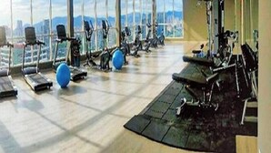A gym with exercise equipment, large windows, and a view of the city. - Titiwangsa Core at TR Residence by HCK (Kuala Lumpur)