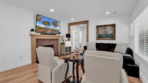 A living room with a fireplace, a television, a sofa, and a painting. - Myrtle Beach Family Retreat-Spacious 4BR (Myrtle Beach)
