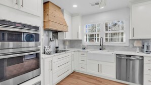 A modern kitchen with white cabinetry, stainless steel appliances, and a wooden ceiling vent. - Myrtle Beach Family Retreat-Spacious 4BR (Myrtle Beach)