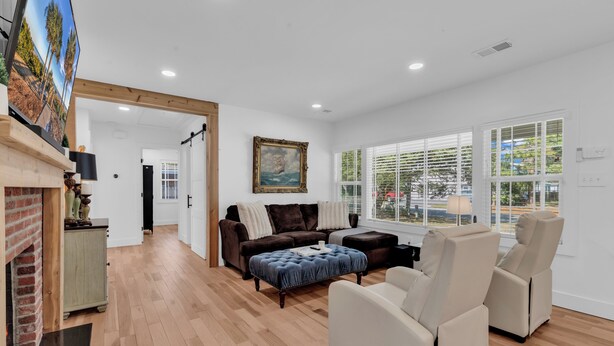 A spacious living room with a fireplace, a large window, and a painting on the wall. - Myrtle Beach Family Retreat-Spacious 4BR (Myrtle Beach)