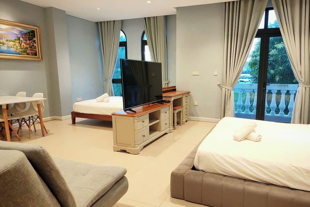 Une chambre d’hôtel avec un lit, une télévision, un bureau et un balcon.