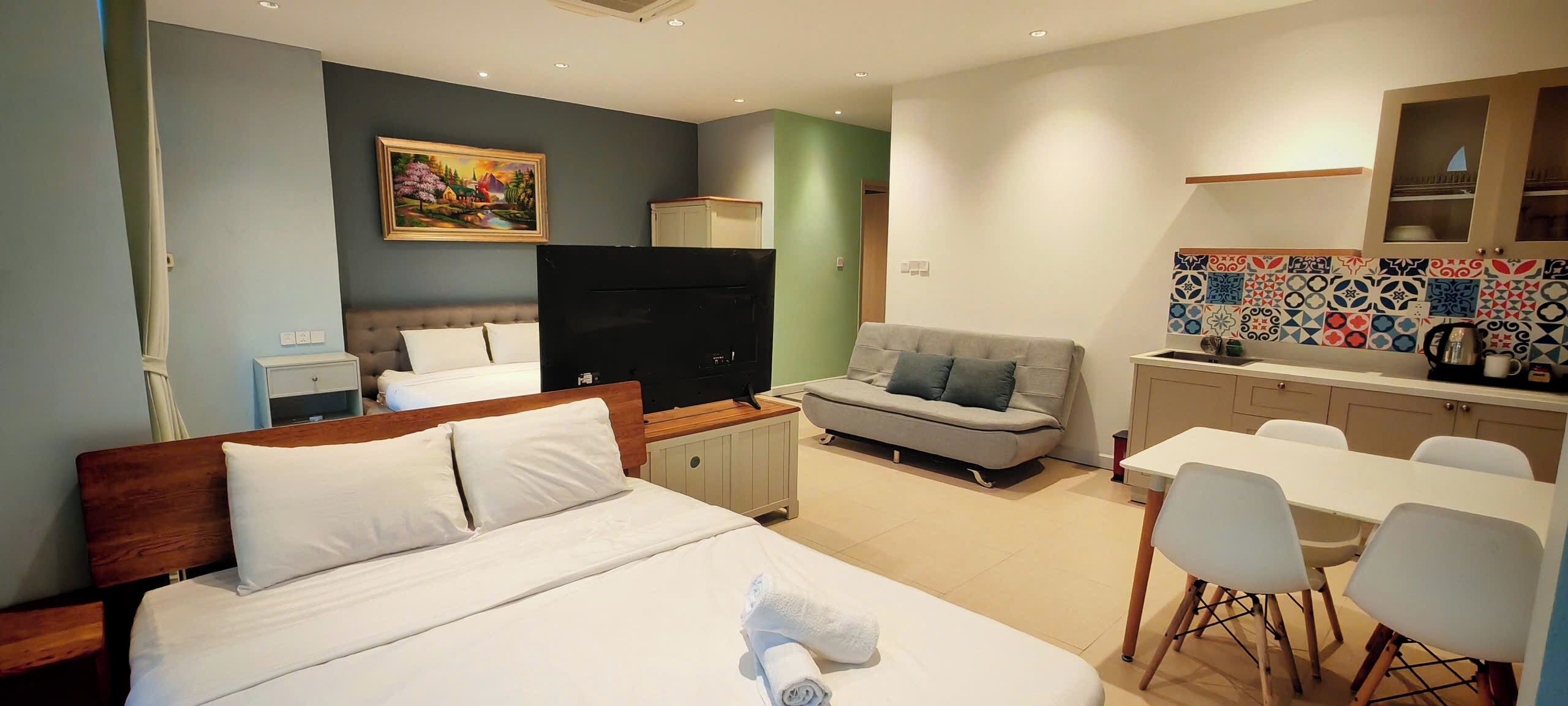 Een hotelkamer met een bed, een bank, een eettafel en een keukenhoek.