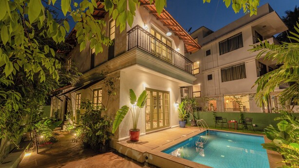 Ein zweistöckiges Haus mit Swimmingpool, umgeben von Topfpflanzen und einer Terrassenanlage.
