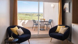 Una camera d'albergo moderna con un balcone, due poltrone, un tavolino e un letto.