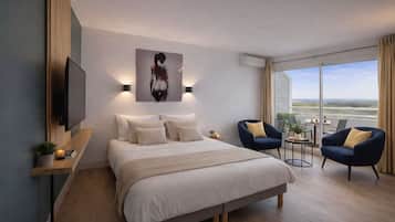 Habitación de hotel moderna con una cama grande, televisión, un cuadro y vistas al paisaje.