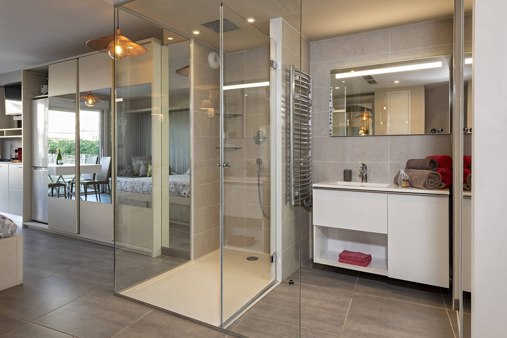Een moderne badkamer met een glazen douchecabine, een witte wastafel en een spiegel.