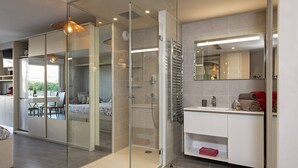 Ein modernes Badezimmer mit Duschkabine aus Glas, einem weißen Waschbecken und einem Spiegel.