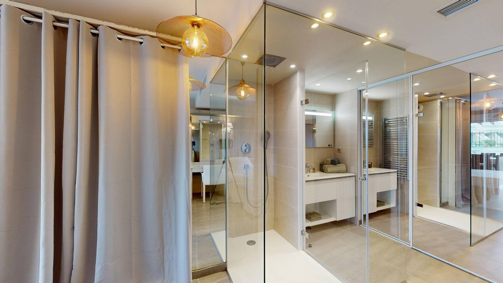 Un baño moderno con cabina de ducha de vidrio, un espejo y una lámpara colgante.