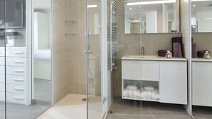 A modern bathroom with a glass shower enclosure, a vanity with a mirror, and a toilet. - NAUTILIA  103 - Premium Luxe - Jacuzzi - 2 people (AGDE)