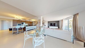Un espacio habitable moderno con comedor, cocina y un amplio ventanal con cortinas.