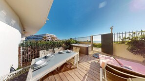 Eine Dachterrasse mit Esstisch, einer Sitzecke für ein Whirlpool und Blick auf das Meer.