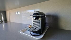 A compact espresso machine on a countertop with a tray. - NAUTILIA  202 - Premium Luxe - Balcony - 2 people (AGDE)