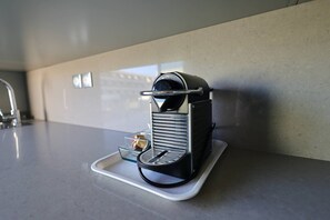 A compact espresso machine on a countertop with a tray. - NAUTILIA  202 - Premium Luxe - Balcony - 2 people (AGDE)