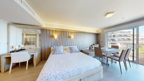 A modern hotel room with a large bed, a desk, a chair, and a dining table. - NAUTILIA  202 - Premium Luxe - Balcony - 2 people (AGDE)