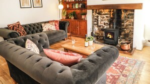 Una sala de estar acogedora con chimenea, un conjunto de sofás, una mesa de centro de madera y una estantería.