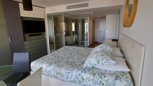 A modern bedroom with a bed, a glass table, a TV, and a wardrobe. - NAUTILIA  205 - Superior Luxe - Terrace - 2 people (AGDE)