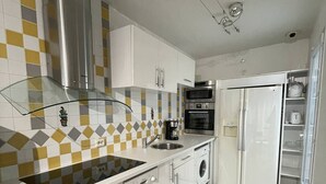 A modern kitchen with white cabinets, a stainless steel range hood, a built-in oven, a dishwasher, and a refrigerator. - BUBBLE Natura Beach - Apartement NB2 - Luxe - 6 people (AGDE)
