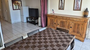 A dining area with a checkered table, a television, a cabinet, and artwork on the wall. - Apartment Natura Beach 203 with parking space - 4 people (AGDE)