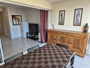 A dining area with a checkered table, a television, a cabinet, and artwork on the wall. - Apartment Natura Beach 203 with parking space - 4 people (AGDE)